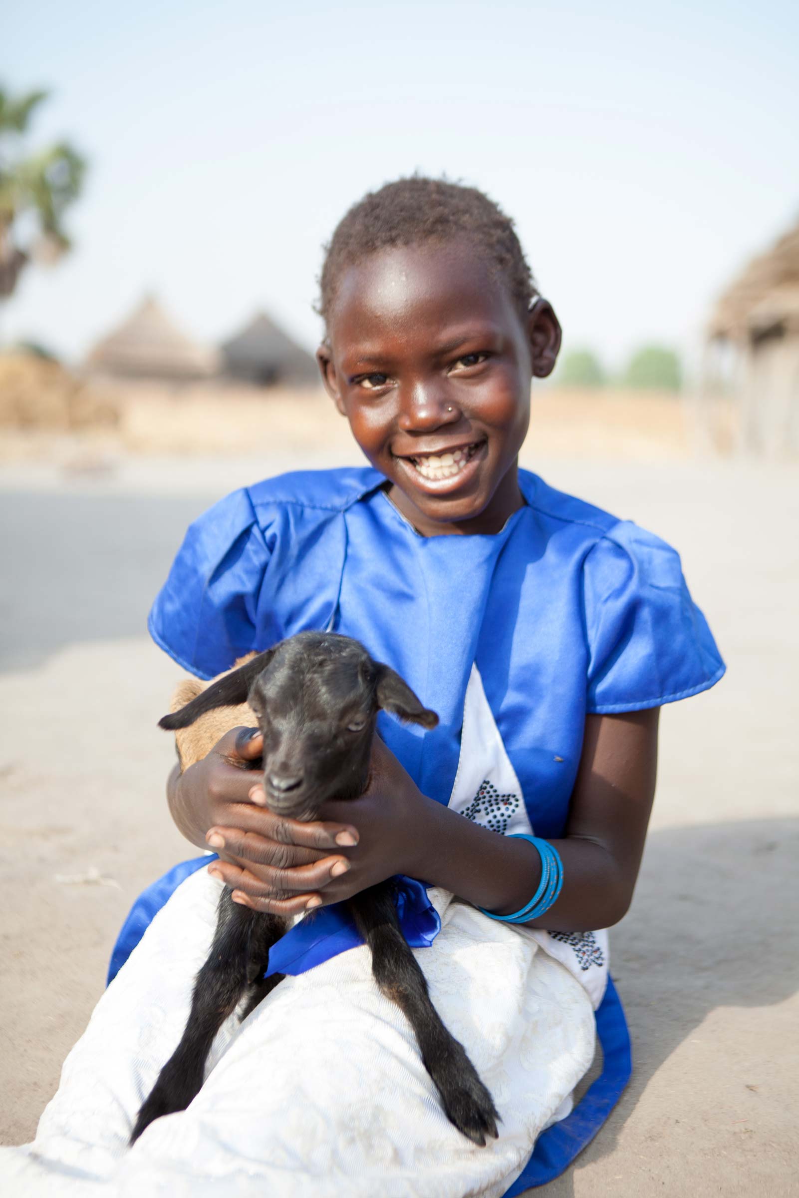 A girl smiles as she holds her goat!