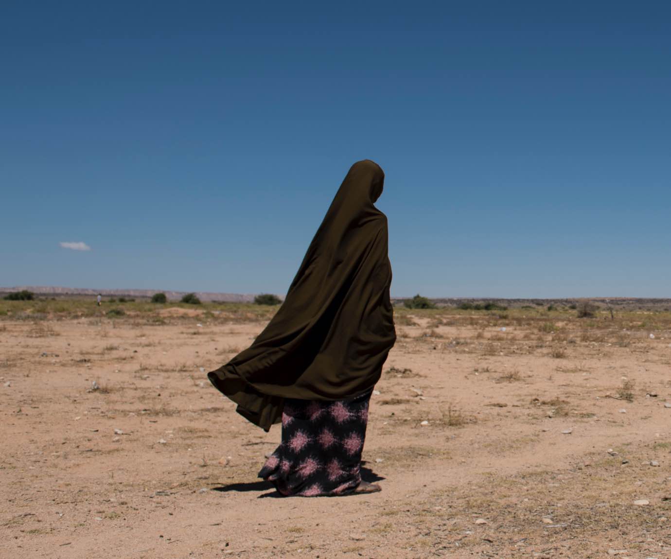 Woman walking across dry landscape