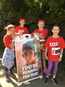 four girls standing around a poster during a run to stop child trafficking