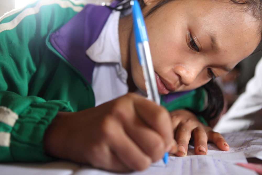 A young girl works hard in her classroom in Laos. 