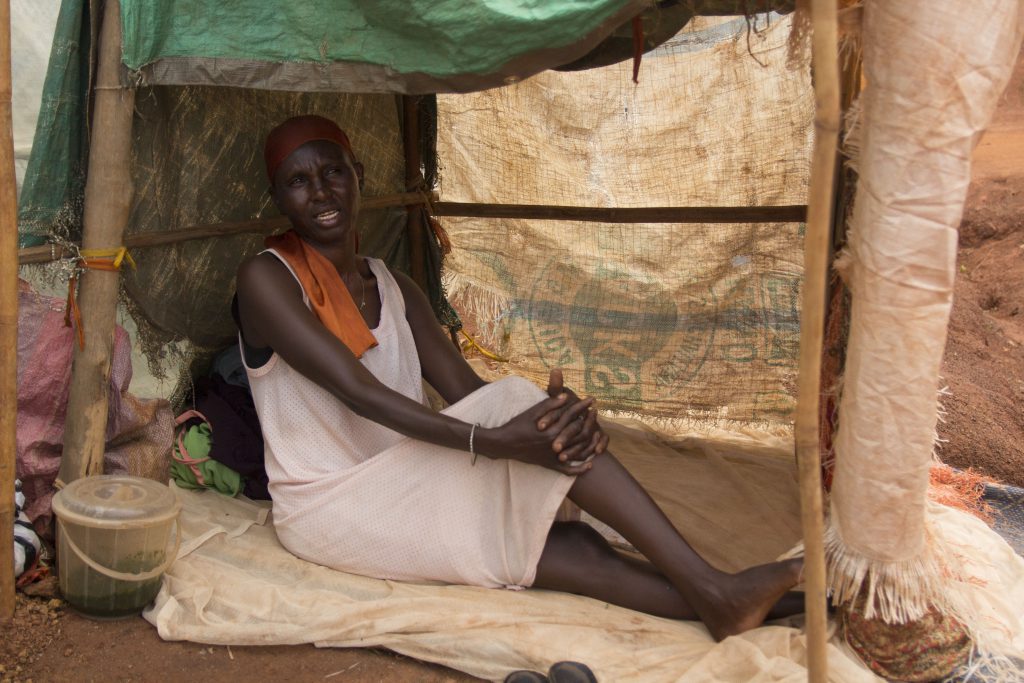 Gisma sits under a makeshift shelter in a camp for displaced families