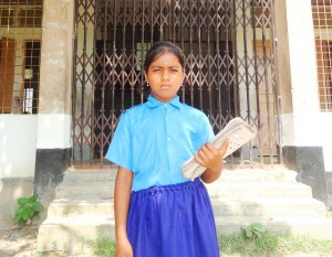 Mitu, now 8 years old, in front of her school.