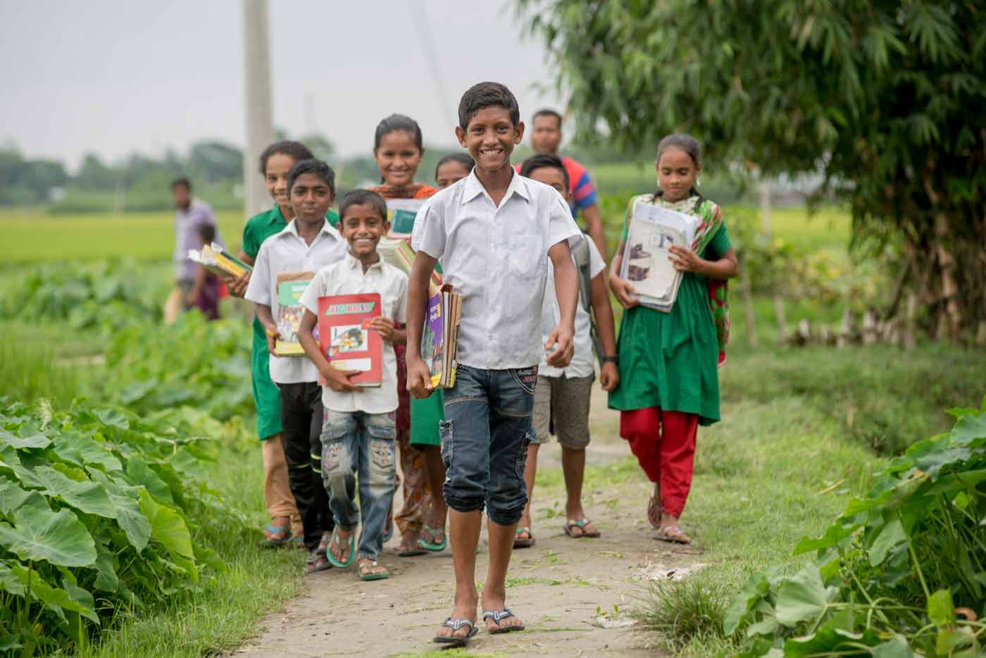 a boy walks with other children on a path to school