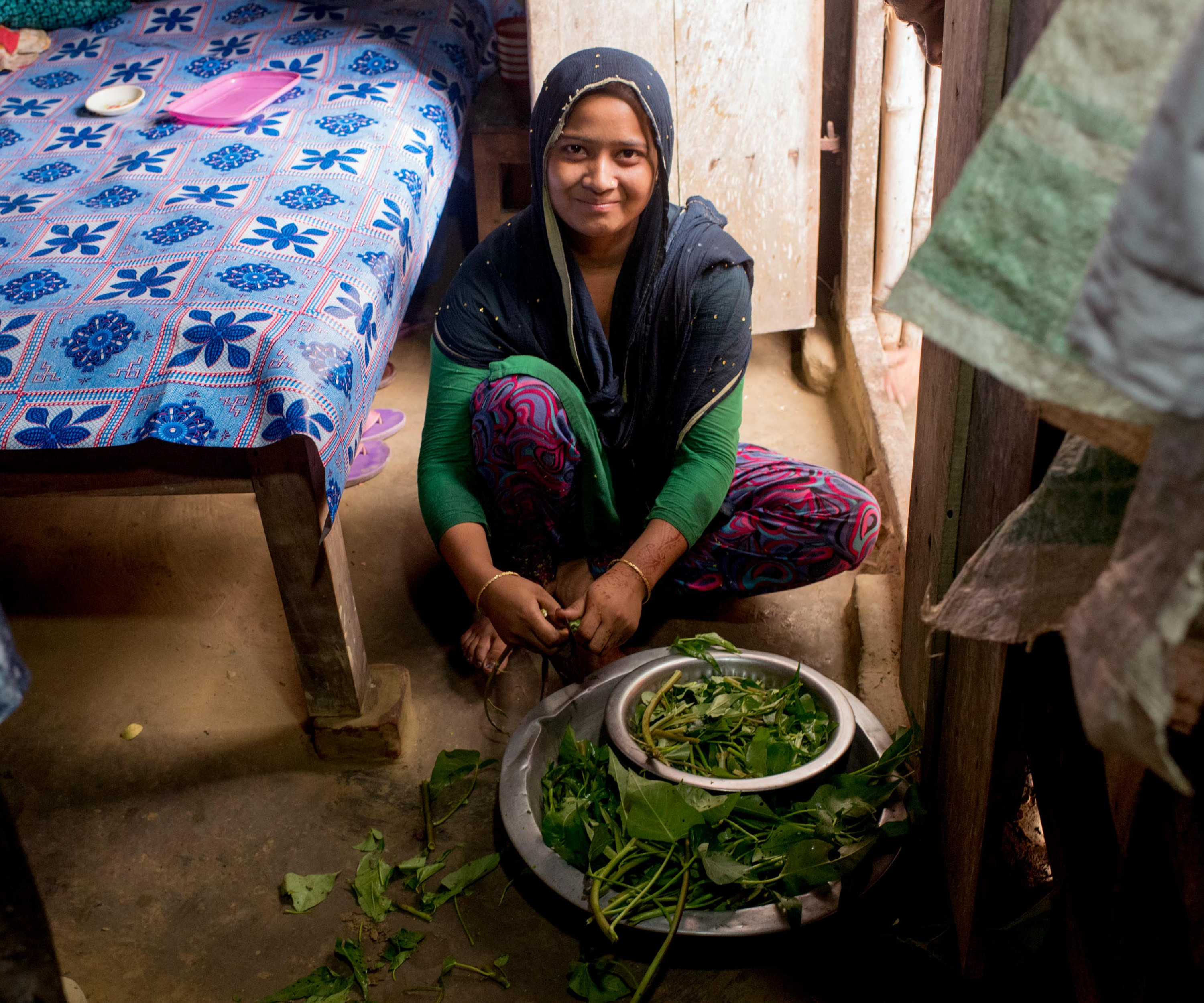 A Bangladeshi woman cuts vegetables inside her home.