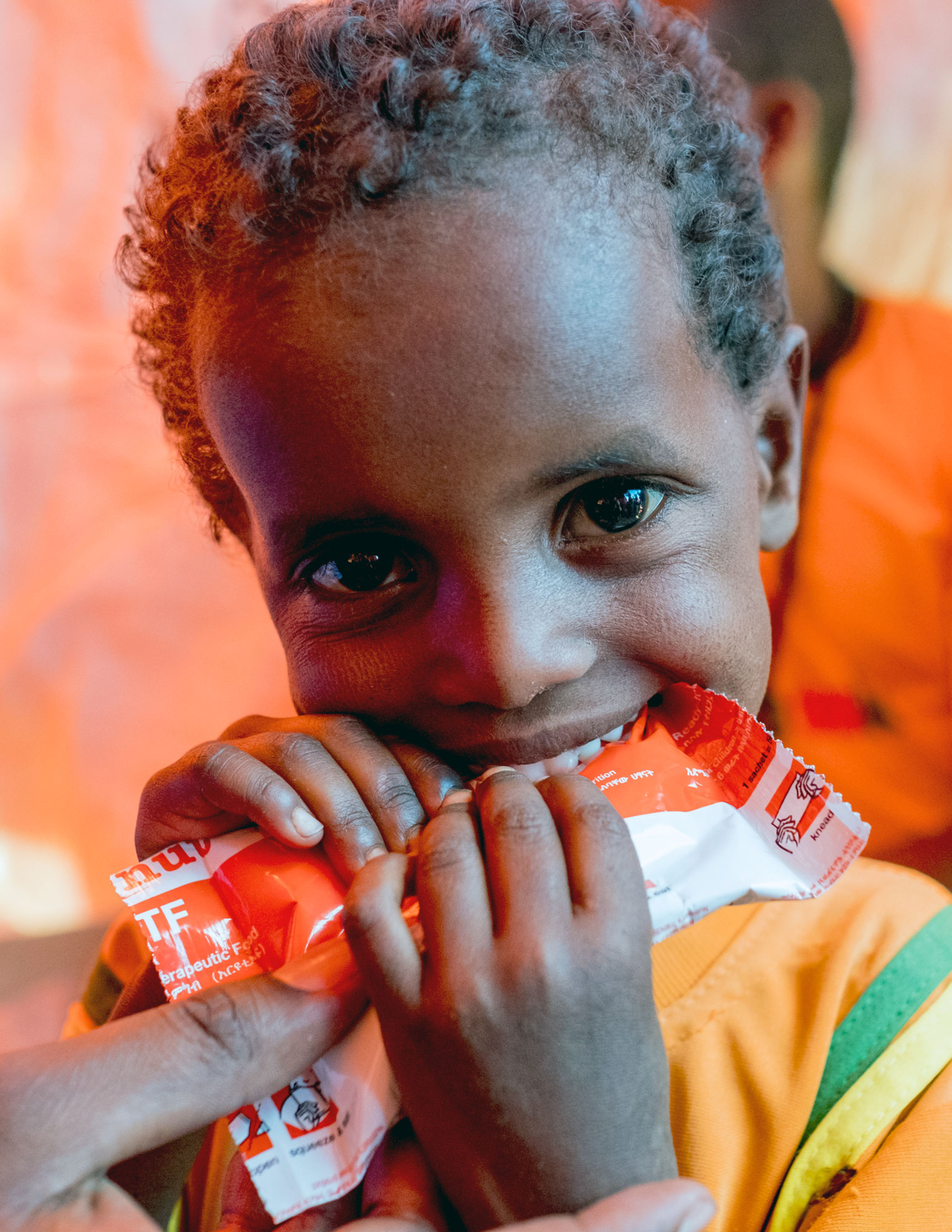 A young Somali boy eats a nutripacket full of emergency nutrition.