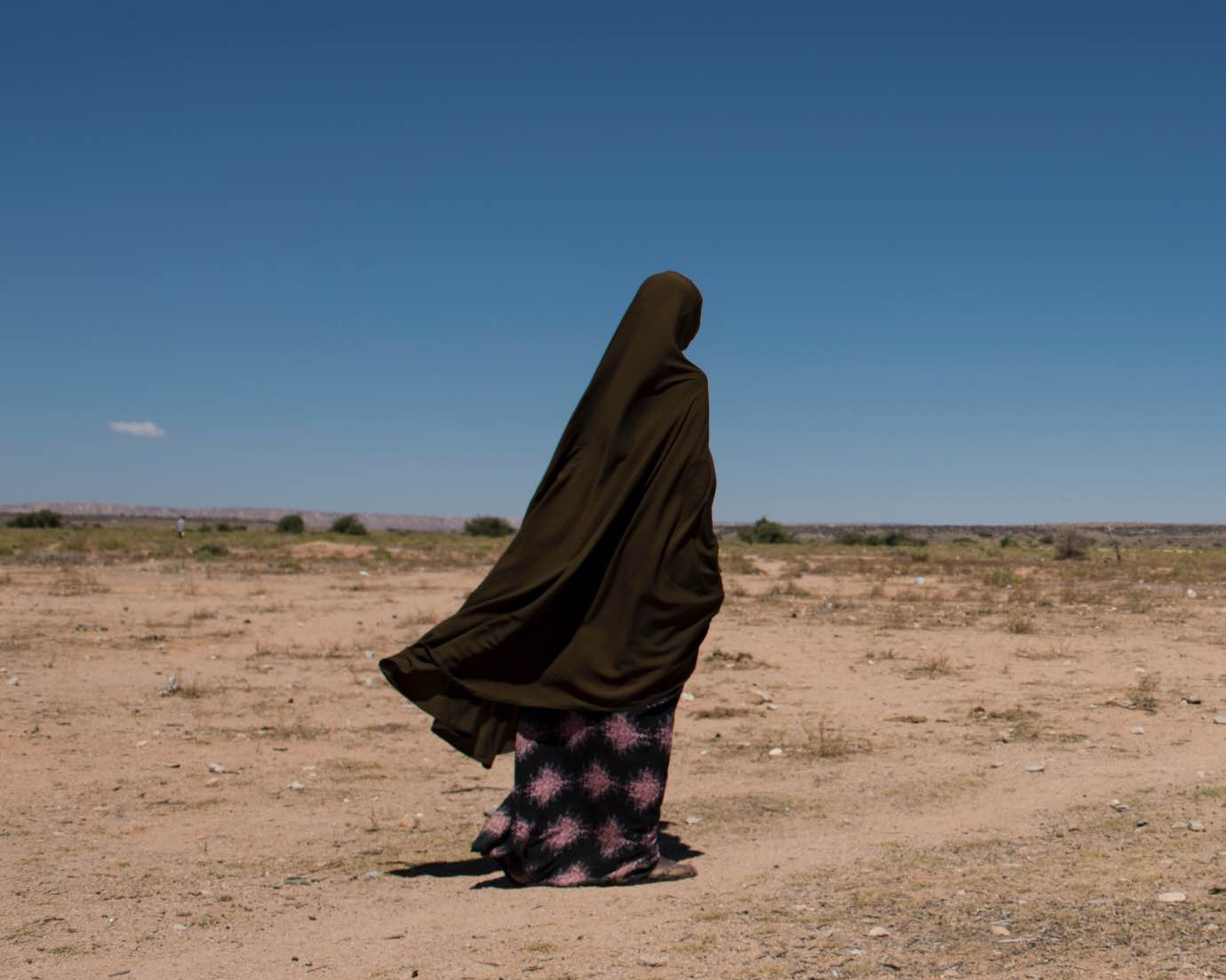 Woman walking across dry landscape