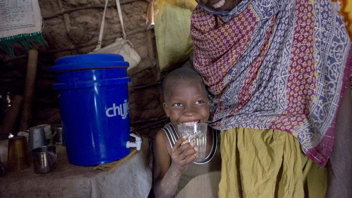 A boy drinks water from a water filter in Kenya.