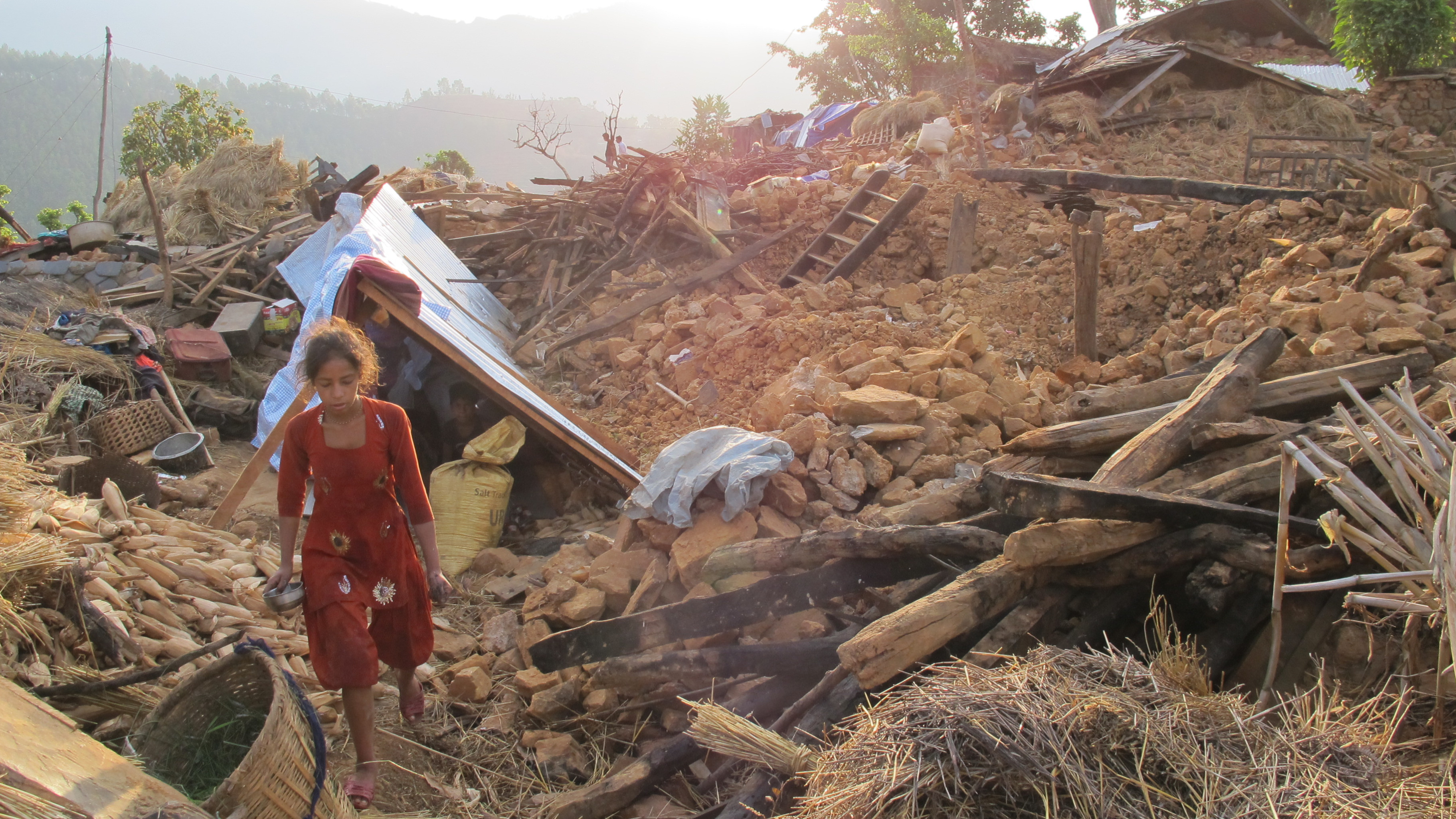 A young girl walks near her tent amidst the rubble in Khalte, Nepal.