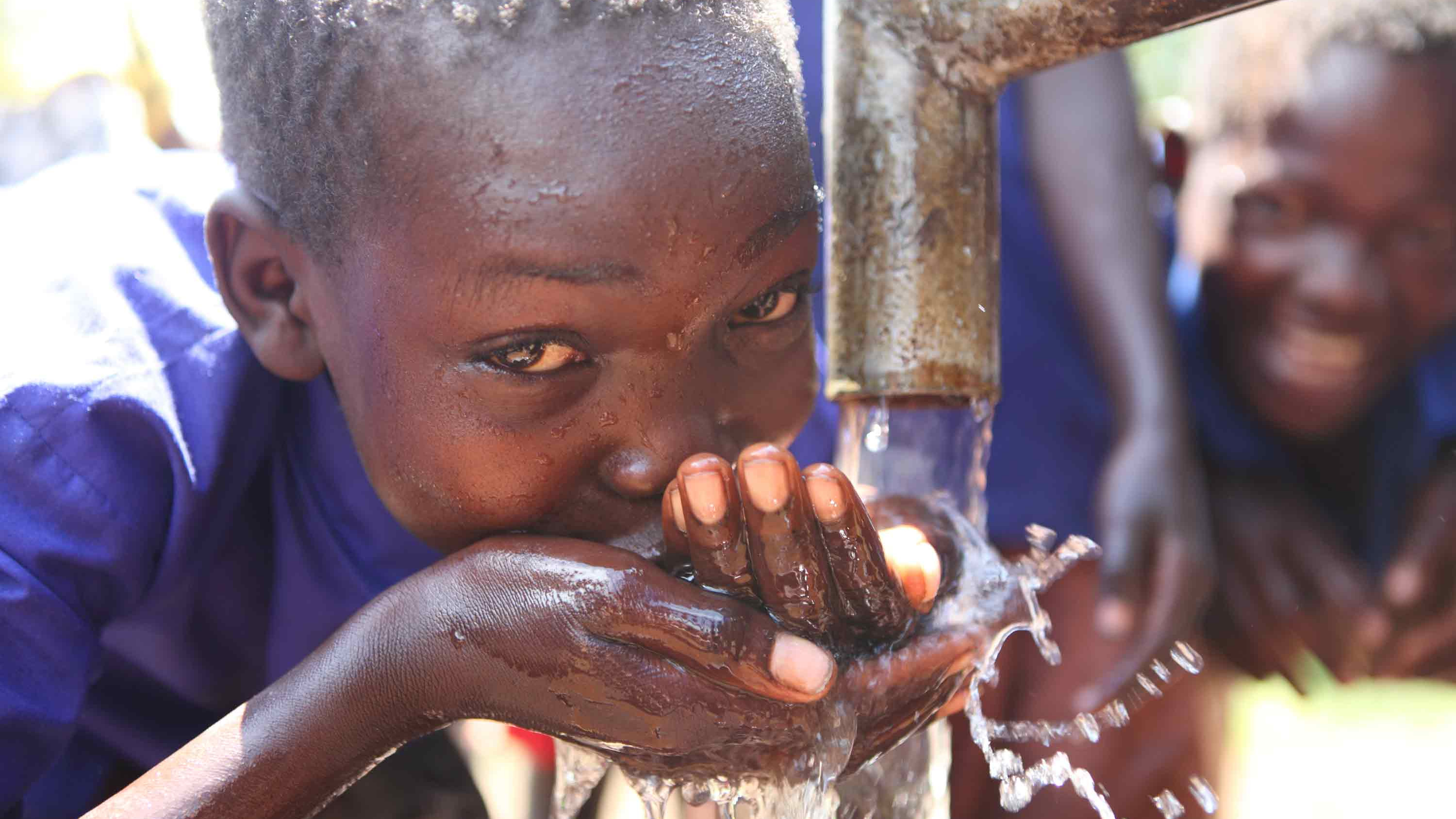 A boy in South Sudan drinks clean water from a well.