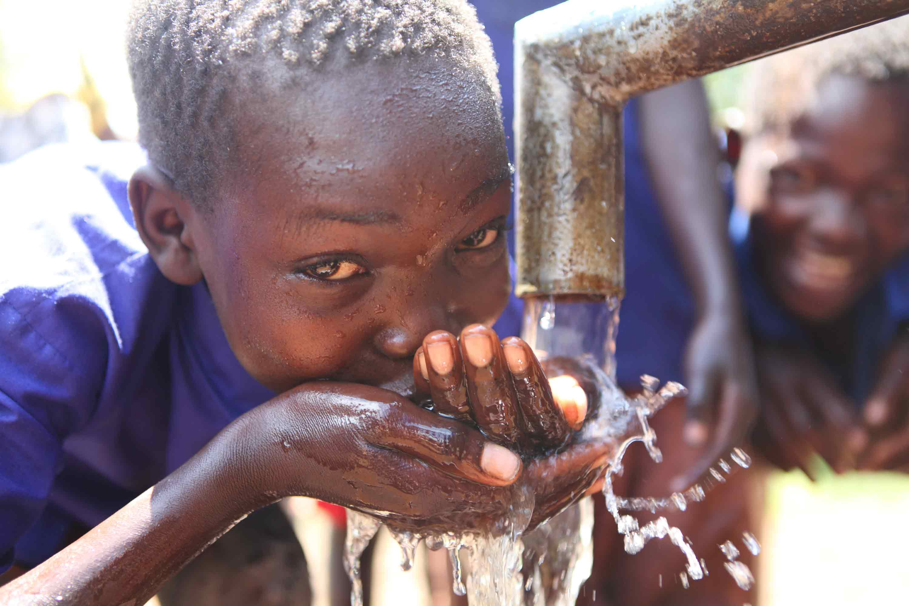 A boy in South Sudan drinks clean water from a well.